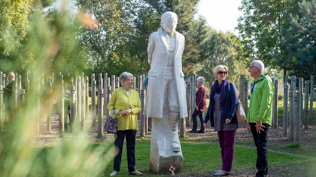 group looking at statue in the National Memorial Arboretum Theobolds coaches day trip